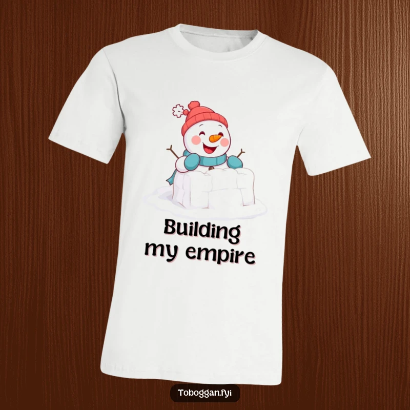 Funny T-Shirt: A cheerful snowman comically tries to build a tiny snowball fort, showcasing winter fun and determination.